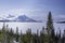 Scandinavian mountain range covered by ice and snow, frozen lake, blue skies, pine forest