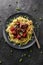 Scandinavian style comfort food. Linguine pasta and homemade meatballs with green peas, red berry sauce and cheese on black plate