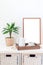 Scandinavian style home interior with empty white board, copy space for mockup. White shelves, green palm in pot, wooden tray with