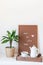 Scandinavian style home interior with white shelves, green palm in  pot, wooden tray with tea, and pegboard with the inspiring