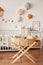 Scandinavian style white interior children`s room, bedroom, nursery. Baby cot with canopy. Wooden shelves and toys. Wicker cradle