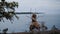 a scarecrow made of branches stands against the backdrop of a clear lake in the mountains