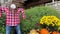 A scarecrow in a red plaid shirt stands with his tousled straw hair on his head shoots the straw and pumpkins lying on