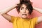 Scared confused beautiful woman posing isolated over pink wall background