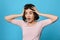 scared curly young brunette woman on blue background.