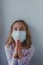 A scared European girl in a mask against coronavirus prays to God that the quarantine and infection will end covid
