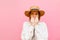 Scared girl in hat and shirt isolated on pink background, looks away with shocked face. Frightened lady lady, closeup portrait on