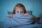 Scared little girl covering face with hands in fear in darkness at night