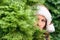 Scared, open-eyed look of a beautiful girl in a santa claus hat hiding behind a christmas tree. Concept.