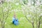 Scared screaming cute little girl with guitar sitting on green grass under blooming trees in spring park