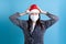 scared upset Asian woman wearing Santa hat and medical protective mask against the virus, holding her head with hands