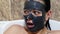 Scared woman with black cleansing cream mask on face