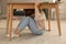 Scared woman hiding under table in living room during earthquake