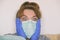 A scared woman sitting at home wearing a protective mask and gloves