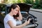 Scared woman in stress holding her head after auto crash calling to auto insurance for help. Driver woman in front of wrecked car