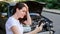 Scared woman in stress holding her head after auto crash calling to auto insurance for help. Driver woman in front of wrecked car