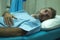 Scared and worried man hospitalized - attractive injured man lying on hospital bed receiving treatment feeling sick and unwell