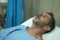 Scared and worried man in pain at hospital room - attractive injured man lying on bed suffering painful problem sick and stressed