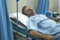 Scared and worried man in pain at hospital room - attractive injured man lying on bed suffering painful problem sick and stressed
