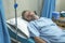 Scared and worried man in pain at hospital room - attractive injured man lying on bed suffering painful problem sick and stressed