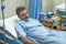 Scared and worried man in pain at hospital room - attractive injured man lying on bed suffering painful problem sick and stressed