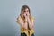 Scared young woman biting nails, disappointed isolated on gray background