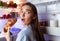 Scared young woman eating croissant near fridge late in night