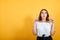 Scared young woman pointing up, afraid, looking shocked on orange wall