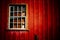 Scary abandoned house with old peeling red wooden wall and grunge broken window under dramatic lighting