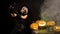 Scary beautiful girl witch celebrates halloween, makes selfie with funny glowing burning pumpkins in smoke. Woman with