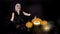 Scary beautiful girl witch laughs, taunts, gloats, celebrates halloween with funny glowing burning pumpkins in smoke