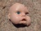 Scary and broken doll face with one blue eye on a background of stone