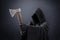 Scary figure in hooded cloak with axe in the dark