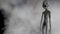 Scary gray alien stands and looks blinking on a dark smoky background. UFO futuristic concept. 3D rendering.