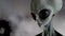 Scary gray alien walks and looks blinking on a dark smoky background. UFO futuristic concept. 3D rendering