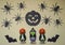 Scary Halloween figurines stand on a light background in close-up, behind hangs terrible pumpkin and spiders