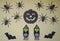 Scary Halloween figurines stand on a light background in close-up, behind hangs terrible pumpkin, spiders and bat