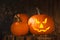 Scary jack o`lantern pumpkin on wooden bench in darkness. Halloween decor