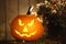 Scary jack o`lantern pumpkin on wooden bench in darkness. Halloween decor