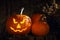 Scary jack o`lantern pumpkin on wooden bench in darkness. Halloween decor