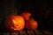 Scary jack o`lantern pumpkin on wooden bench in darkness, space for text. Halloween decor