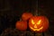 Scary jack o`lantern pumpkin on wooden bench in darkness, space for text. Halloween decor