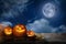 Scary Jack O Lantern pumpkins under moon on Halloween. Space for text