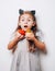 Scary little girl holding decorative pumpkins on white background