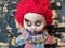 scary and old battered clown doll with burnt face and red hair on the background of burnt wooden board