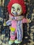 scary and old battered clown doll with burnt face and red hair on the background of burnt wooden board