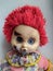 scary and old battered clown doll with burnt face and red hair on the white background