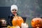 Scary toddler child in halloween costume, playing with carved pumpkins