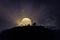 Scary view crowd of zombies on hill with spooky cloudy sky with fog and rising full moon. Silhouette group of zombie walking under