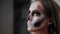 Scary young girl with creative halloween face art in the dressing room. Portrait of glamorous skull with rhinestones and